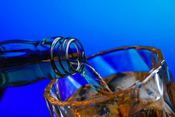 istock Pouring whiskey from bottle into glass with ice 1211578064