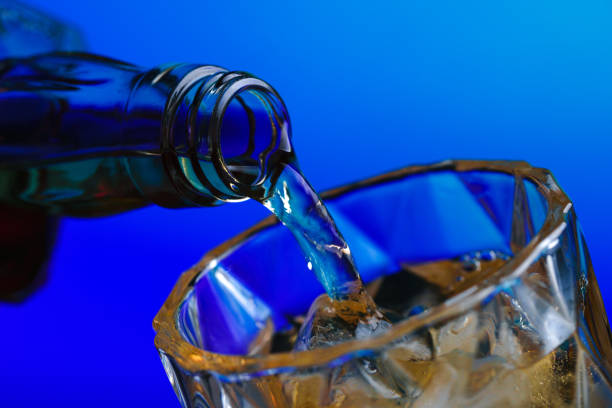 istock Pouring whiskey from bottle into glass with ice 1211578107