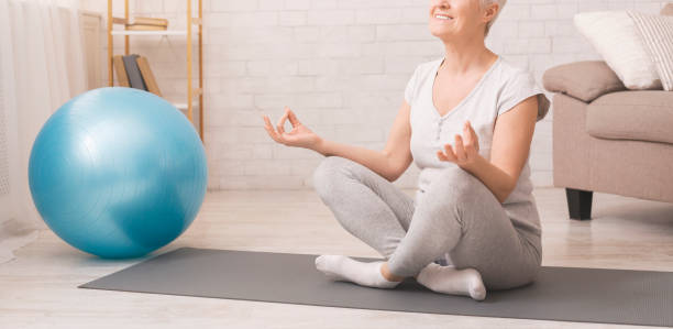 istock Calm senior lady practicing yoga, meditating at home 1211578470