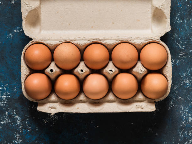 istock Orange chicken eggs in a carton on a dark blue background. Easter concept. Minimalism. Top view. Copy space. 1211578642