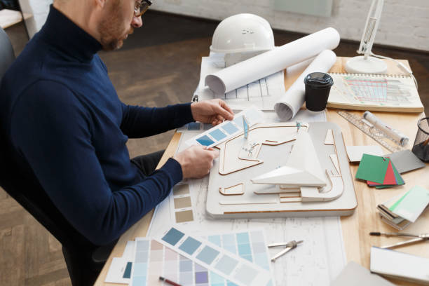 istock Architect working in office with color palette. Engineer select colors for building using color swatches, searching new ideas for construction project. Portrait of handsome bearded man at workplace 1211579543