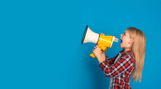 emotional little girl shouting at copy space with megaphone, making announcement - marketing megaphone child using voice imagens e fotografias de stock