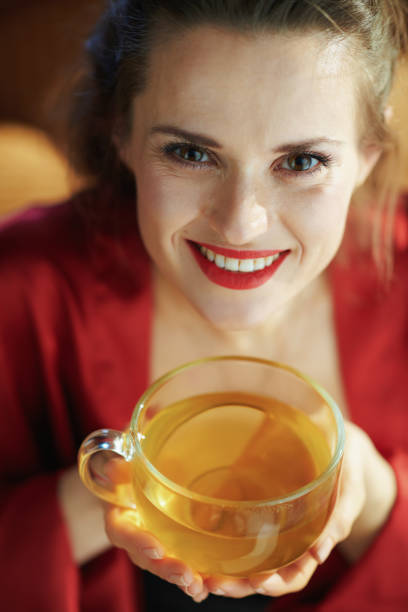 femme avec la tasse de thé vert dans le salon moderne dans le jour ensoleillé - joy the human body smiling women photos et images de collection