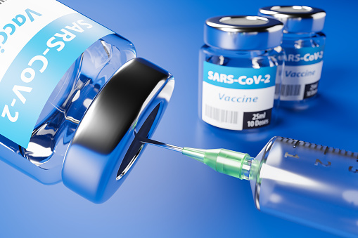 Vacunación contra el nuevo Virus Corona SARS-CoV-2: Dos envases de vidrio con 10 dosis cada uno y una jeringa delante. Enfoque selectivo en primer plano. photo