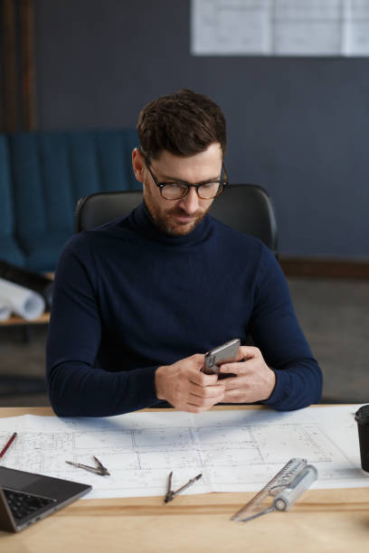 istock Young man using smartphone and smiling. Happy businessman using mobile phone apps, texting message, browsing internet, looking at smartphone. Concept of young people working with mobile devices 1211579859