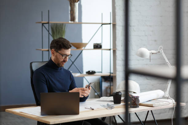 istock Young man using smartphone and smiling. Happy businessman using mobile phone apps, texting message, browsing internet, looking at smartphone. Concept of young people working with mobile devices 1211579877