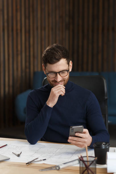 istock Young man using smartphone and smiling. Happy businessman using mobile phone apps, texting message, browsing internet, looking at smartphone. Concept of young people working with mobile devices 1211580208