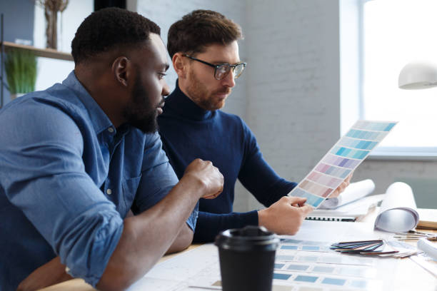 istock Multiracial engineer team working in office with color palette. Architects select colors for building using color swatches, sketching and planning construction project. Partners discussing at work 1211582269