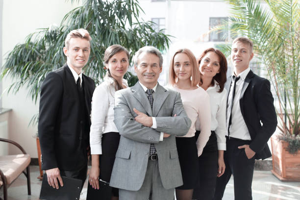 istock Successful business man standing with his staff in background at office 1211582579