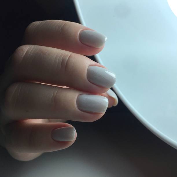 istock Woman's hands with white nails on the dark background 1211582865