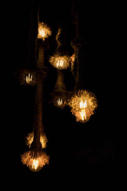 istock vintage style tungsten light bulb hang on ceiling. retro style tungsten light bulb is glowing in the dark 1211587439