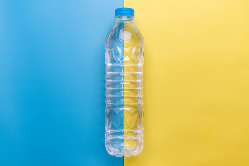 water plastic bottle on yellow and blue background flat lay