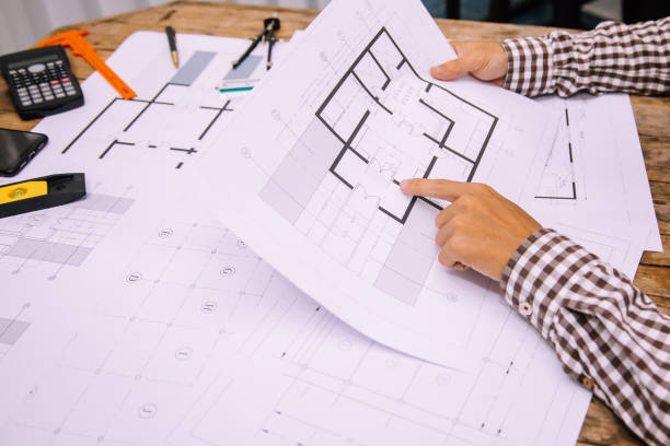 istock Close-up hand of male Architect drawing blueprint on work space in construction site. 1211589742