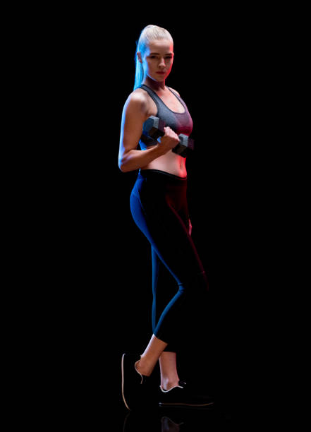istock Exercising in front of black background wearing leggings and being active with weights 1211591259