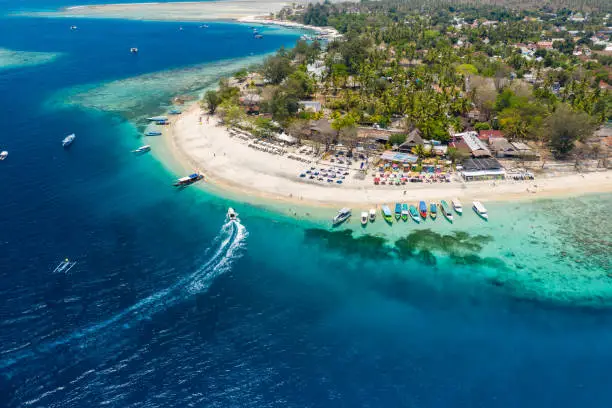 Aerial view of boats moored off a beautiful tropical coral reef and beach on a small island (Gili Air, Indonesia)