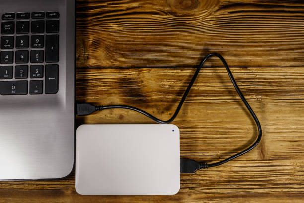 istock External HDD connected to laptop computer on a wooden desk. Top view. Concept of data storage 1211592316