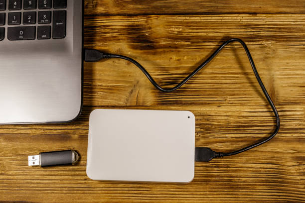 istock External HDD connected to laptop computer and USB flash drive on a wooden desk. Top view. Concept of data storage 1211592318