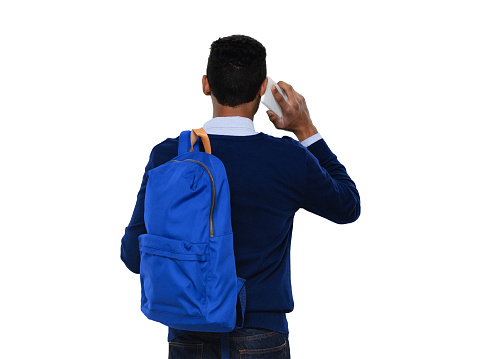 Rear view of aged 20-29 years old with black hair generation z young male in front of white background wearing jeans who is talking and using smart phone