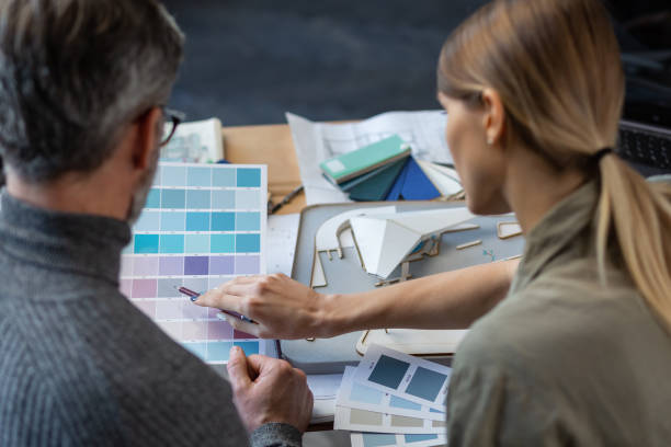 istock Interior designers team working in office with color palette. Architects select colors for building using color swatches, sketching and planning construction project. Partners discussing at work 1211598235