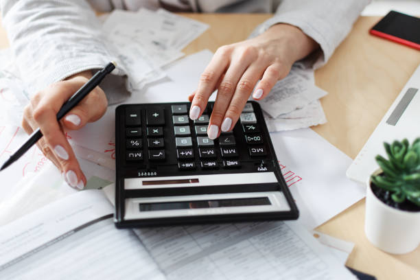 istock Woman holding bills and calculating them. Workplace with computer, calculator, smartphone and documents. 1211603689