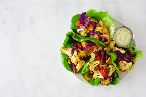 istock Healthy plant based lettuce wraps with grilled cauliflower, top view over a white marble background 1211604653