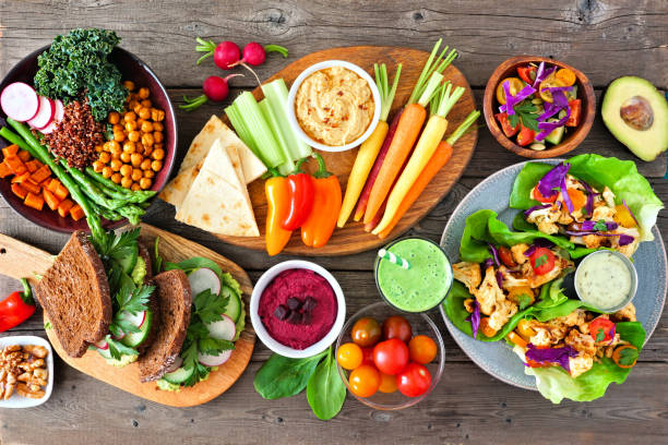 istock Healthy lunch table scene with nutritious Buddha bowl, vegetables, sandwiches, lettuce wraps and salad, above view over rustic wood 1211604708