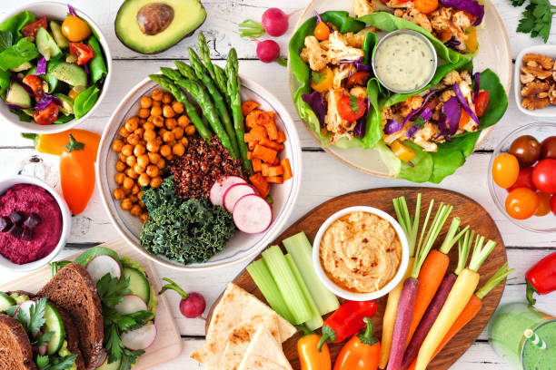 istock Healthy lunch table scene with nutritious Buddha bowl, lettuce wraps, vegetables, sandwiches and salad, top view over white wood 1211604927