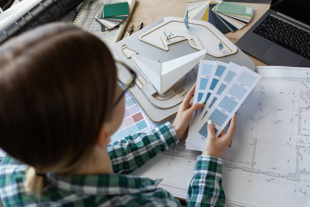 istock Female interior designer working in office with color palette. Architect select colors for building using color swatches, searching new ideas for project. Portrait of beautiful woman at workplace 1211604961