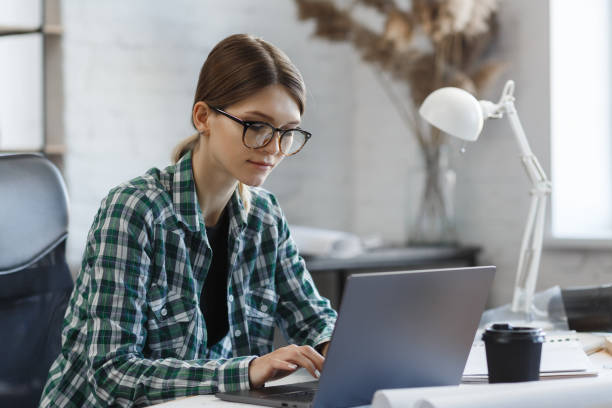 istock Female interior designer working in office with laptop. Architect thinks over architectural plan, searching new ideas for construction project. Woman sitting at workplace. Business portrait concept 1211605054