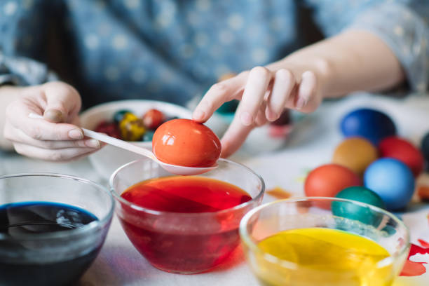 Young girl at home painting colourful Easter Eggs