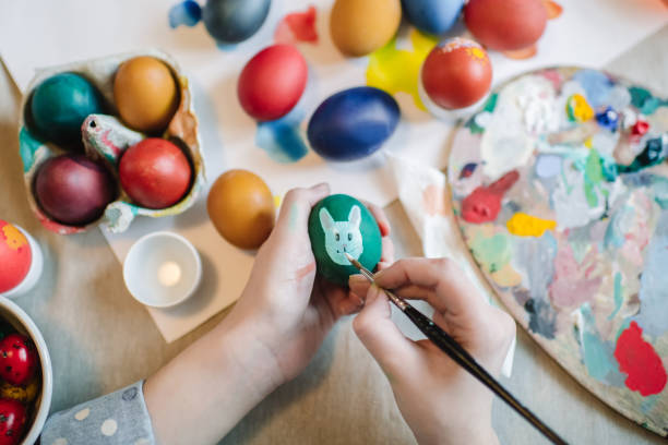 Young girl painting on Easter egg Close up of girl's hands painting on Easter egg easter egg coloring stock pictures, royalty-free photos & images