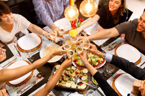 family toasting on dinner table - flower arrangement dining room decor dining imagens e fotografias de stock