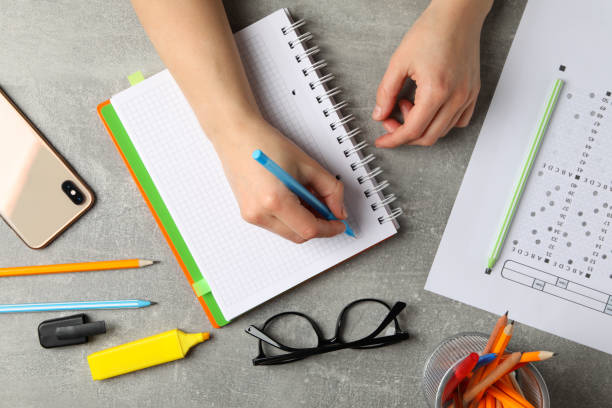 istock Person writes in a notebook on grey background, top view. Exam concept 1211606655