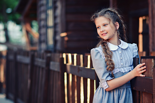 Girl in retro dress on a background of a wooden rural house