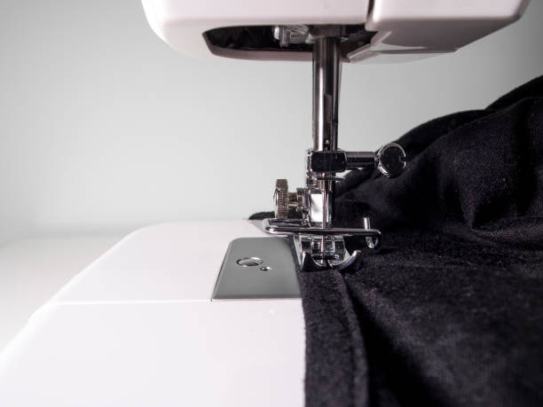 istock Sewing machine detail with a black fabric on a white wall background 1211607990