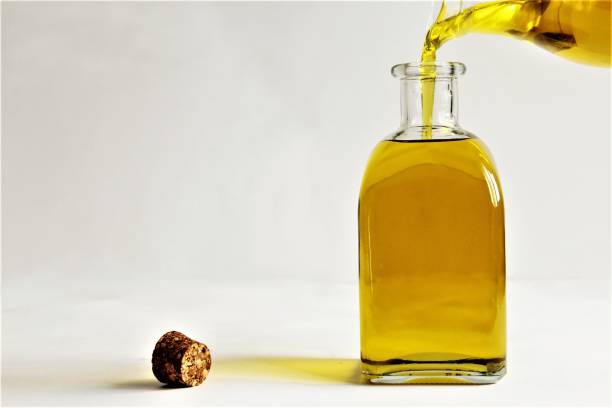 pouring olive oil from glass jar to glass bottle photo - olive oil pouring antioxidant liquid imagens e fotografias de stock