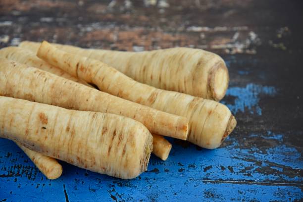 istock Fresh parsnips on blue wooden background 1211610693