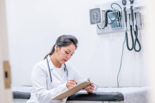 istock Doctor Taking Notes in Exam Room stock photo 1211613791