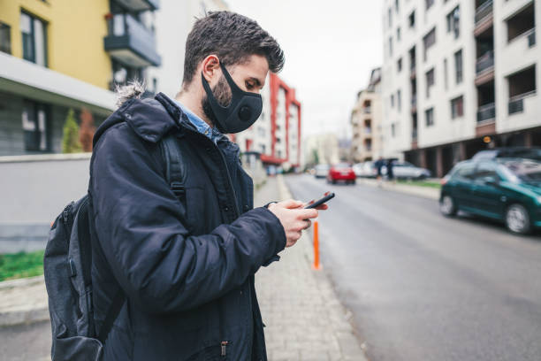 jeune homme dans la rue utilisant le masque anti-pollution - antipollution photos et images de collection