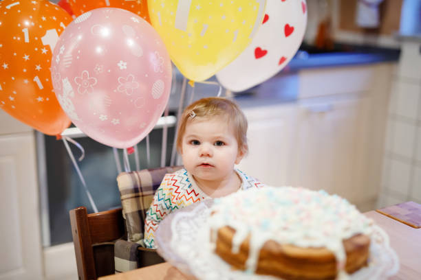 adorável garotinha comemorando primeiro aniversário. bebê comendo decoração marshmellows em bolo caseiro, interior. festa de aniversário para criança fofa, linda filha - birthday cake family germany indoors - fotografias e filmes do acervo