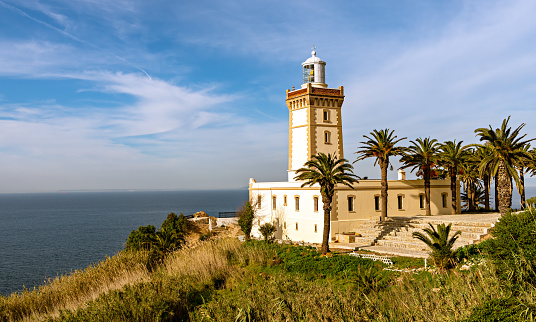 View of the lighthouse on cape Spartel, surrounded by palm trees, on the Atlantic ocean coast of Tangier, Morocco