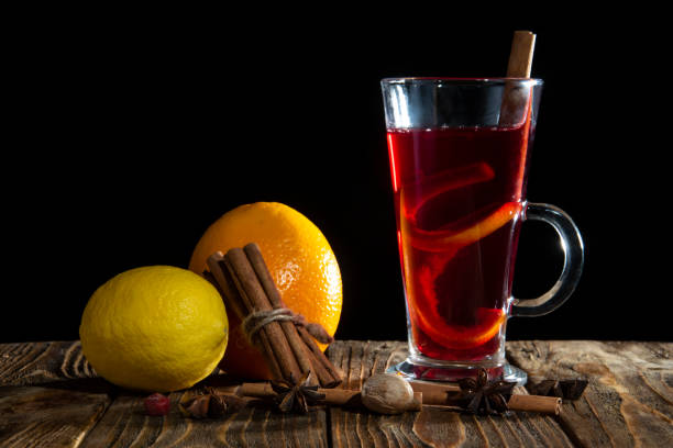 Mulled wine with orange peel, cinnamon sticks and star anise and citrus on a wooden table on a black background. Mulled wine with orange peel, cinnamon sticks and star anise and citrus on a wooden table.Black background. кружка stock pictures, royalty-free photos & images