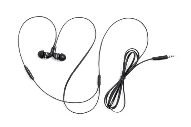 Earphones headset on a white background. Ear plugs for music lovers in the shape of a heart. Vacuum wired black headphones for listening music and sound on portable devices. In-ear headphones.