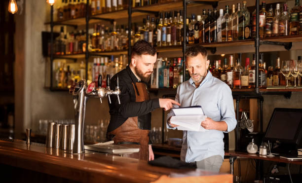 Keeping track of the stock Shot of a bar manager and bartender checking the stock in the pub bar drink establishment stock pictures, royalty-free photos & images