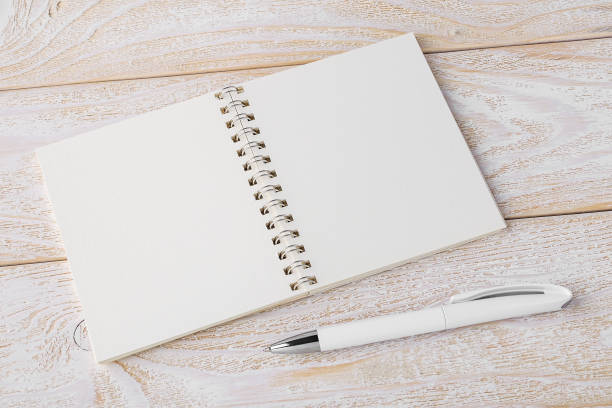 istock Opened spring notepad and white ballpoint pen on a white wooden textured surface. Business, education, keep a diary and write notes concept. 1211625315