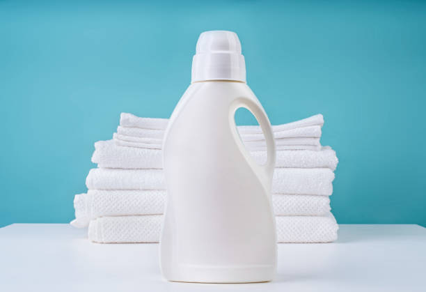 stack of clean white towels and a bottle of detergent on blue background Laundry concept. Stack of clean white towels and a bottle of detergent on blue background with copy space fabric softener photos stock pictures, royalty-free photos & images