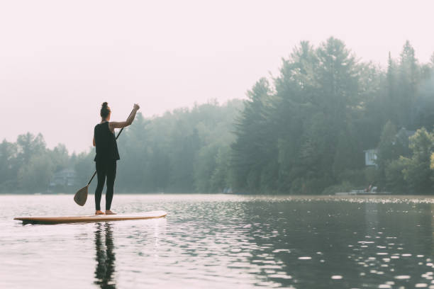 istock Young Woman Paddleboarding On A Calm Lake 1211628803