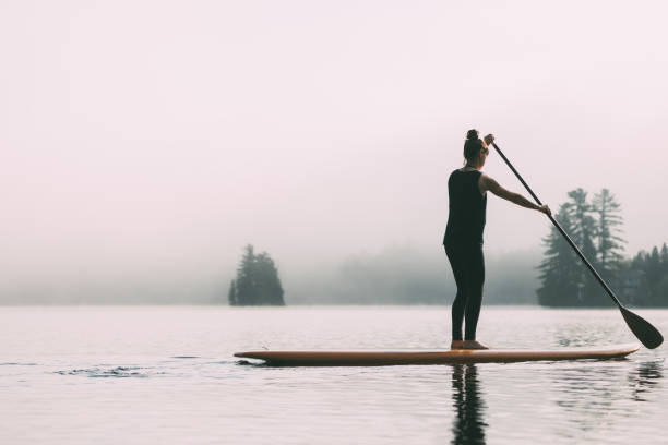 istock Young Woman Paddleboarding On A Calm Lake 1211628813
