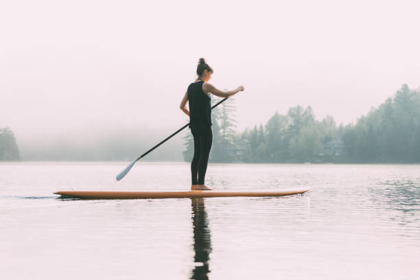 istock Young Woman Paddleboarding On A Calm Lake 1211628827