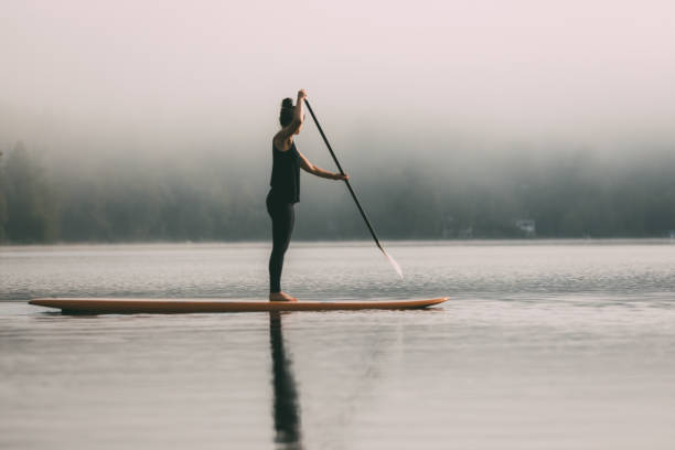 istock Young Woman Paddleboarding On A Calm Lake 1211628851